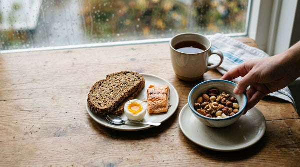 Ontbijttafel met noten, volkorenbrood, ei en zalm als natuurlijke bronnen van sporenelementen.